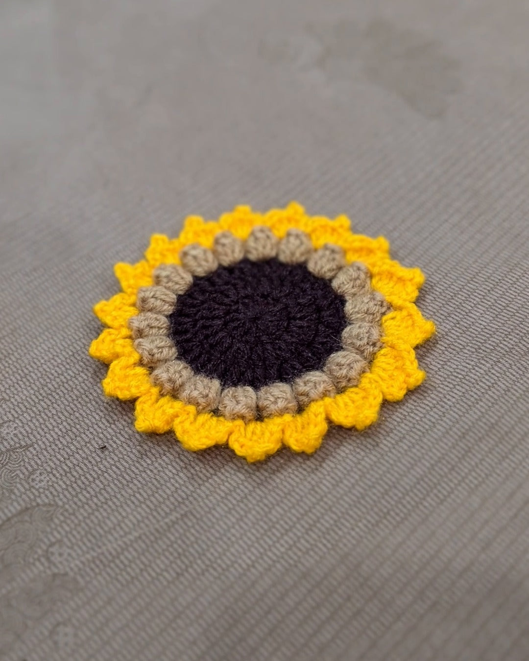 A crochet sunflower coaster lying flat