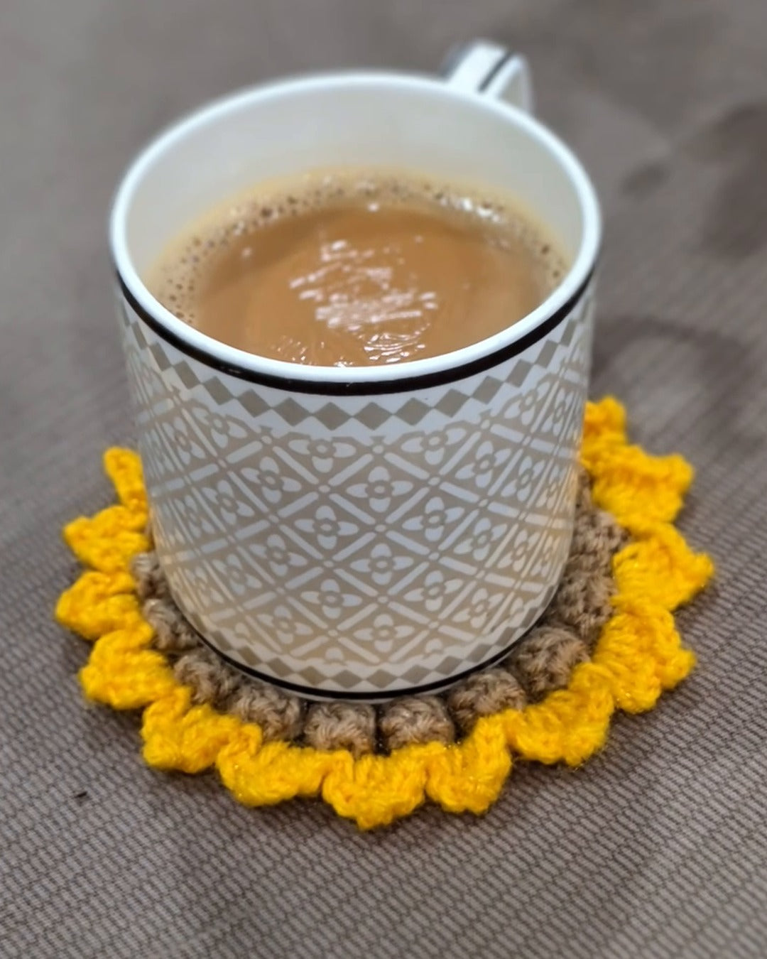 A cup of chai resting on a crochet sunflower coaster